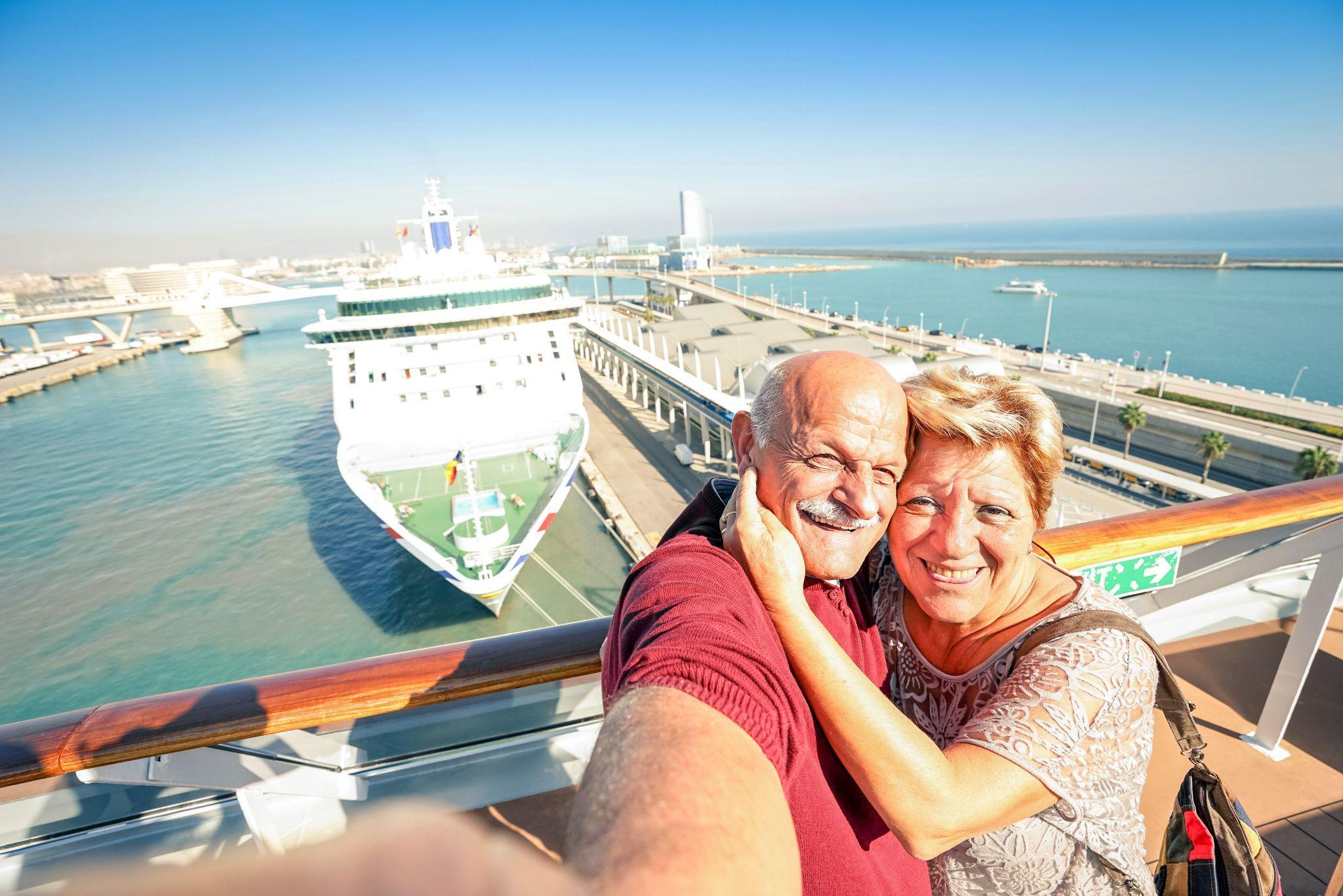 Senior happy couple taking selfie on cruise ship with harbor background