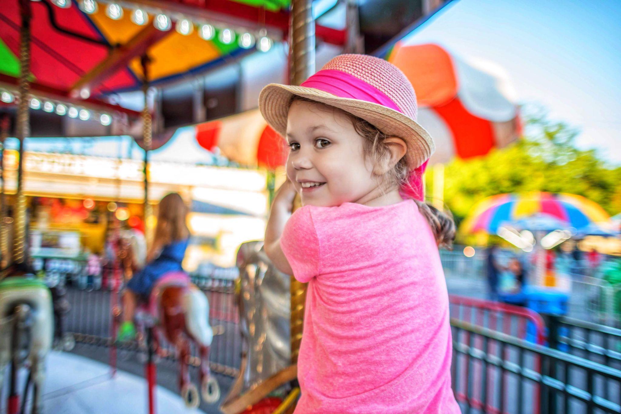 Little girl on a merry-go-round at an amusement park having fun