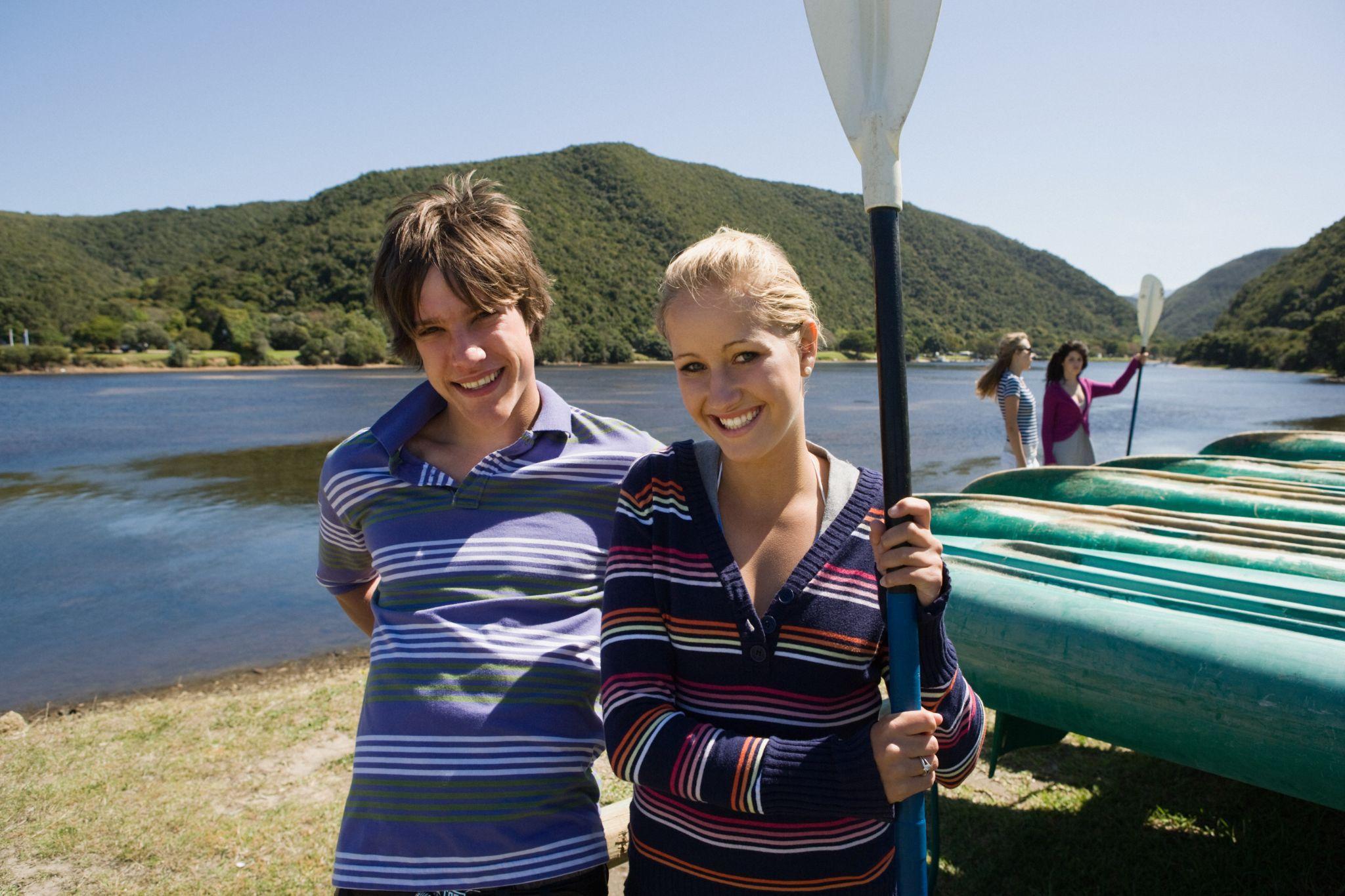 Teenagers prepared to rent a canoe holding paddles