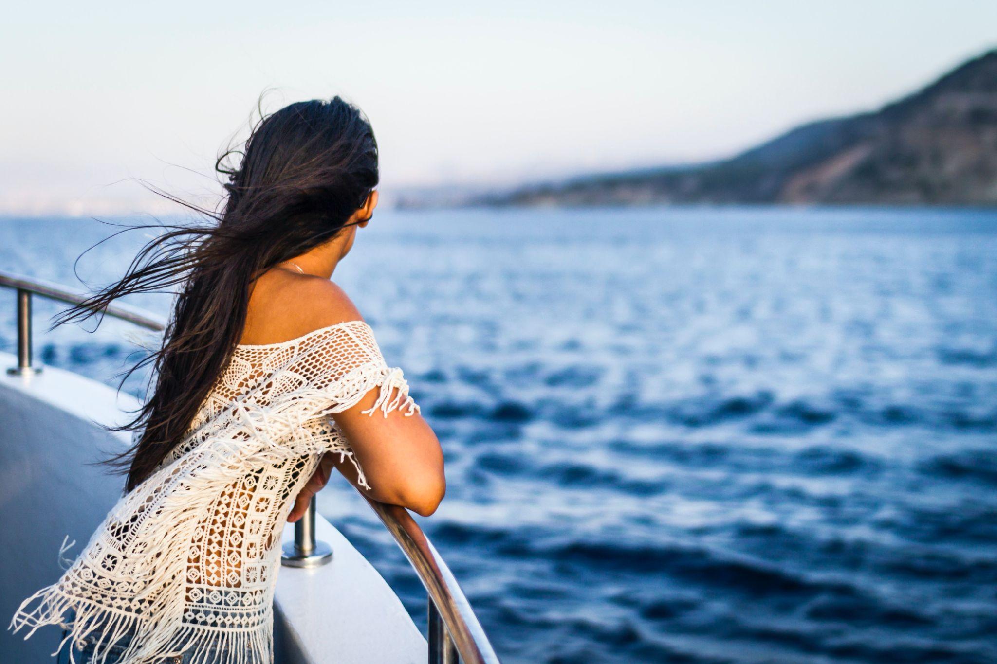 Woman looking at the sea with the knowledge that she is covered by a cruise insurance plan.