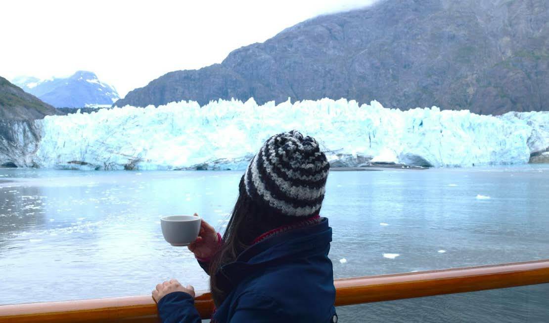 Enjoy a cup of coffee on a cabin's veranda with a beautiful view of glaciers on an Alaskan cruise.