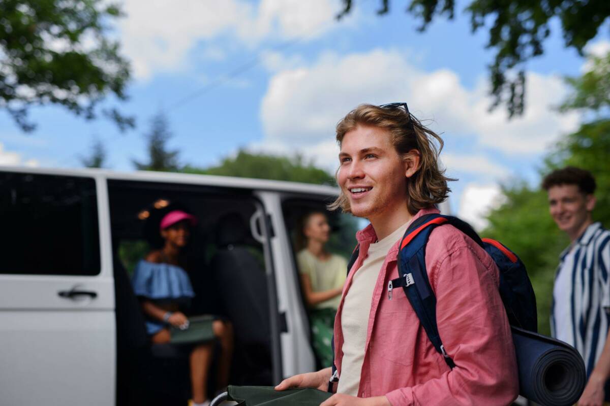 Group of young travelers in a van arriving at their airbnb rental.