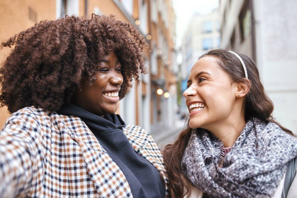 Two women taking a selfie laughing in the city outdoors for tourism or adventure overseas travel