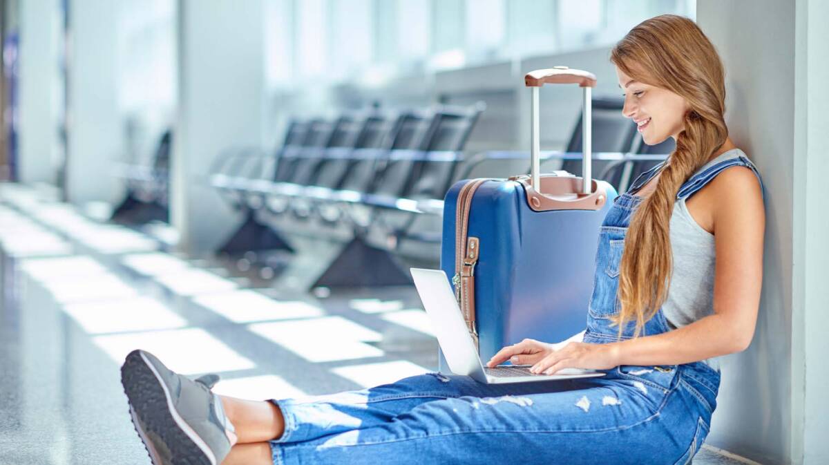 A young women siting in the airport with a luggage and laptop.