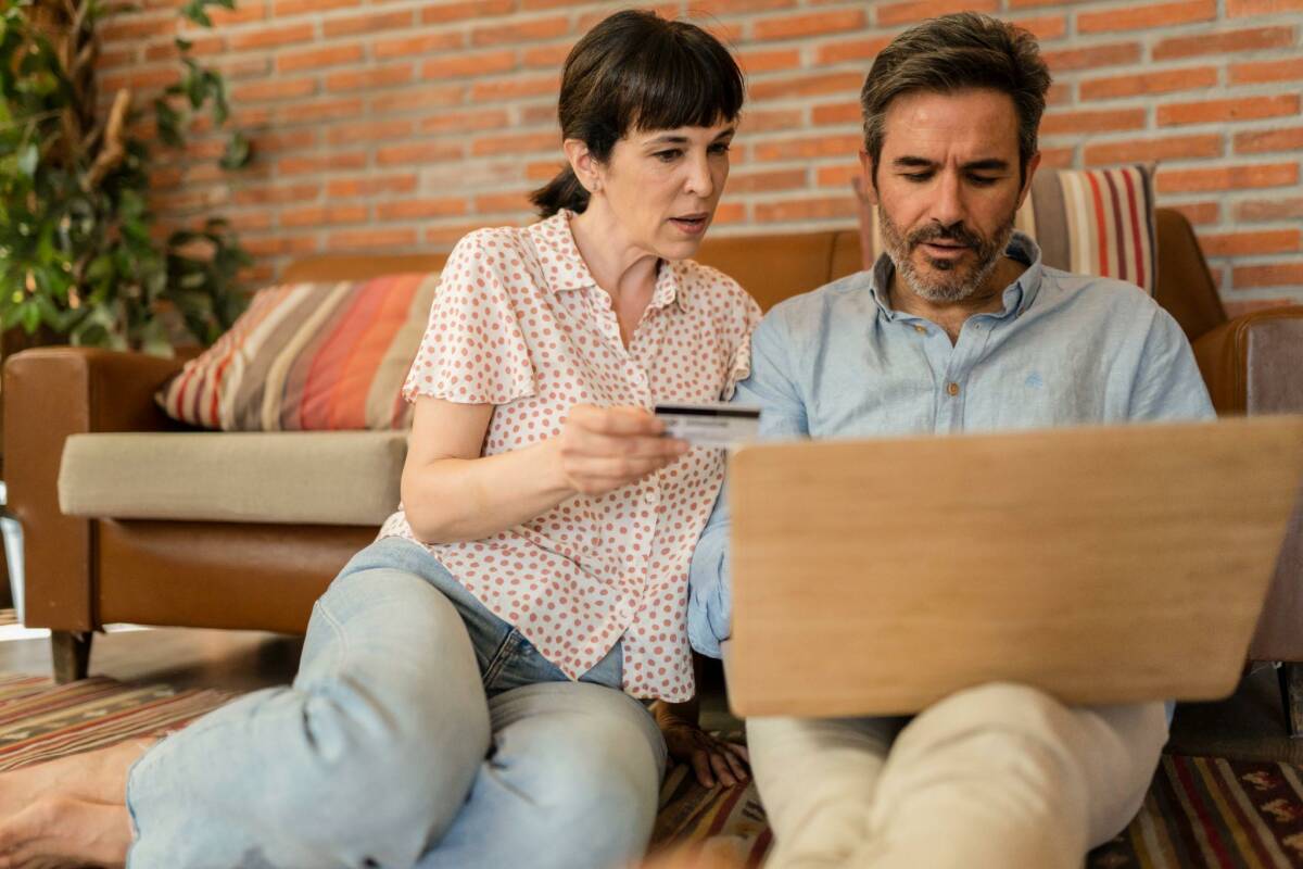 A couple using a laptop to review the credit card travel insurance.