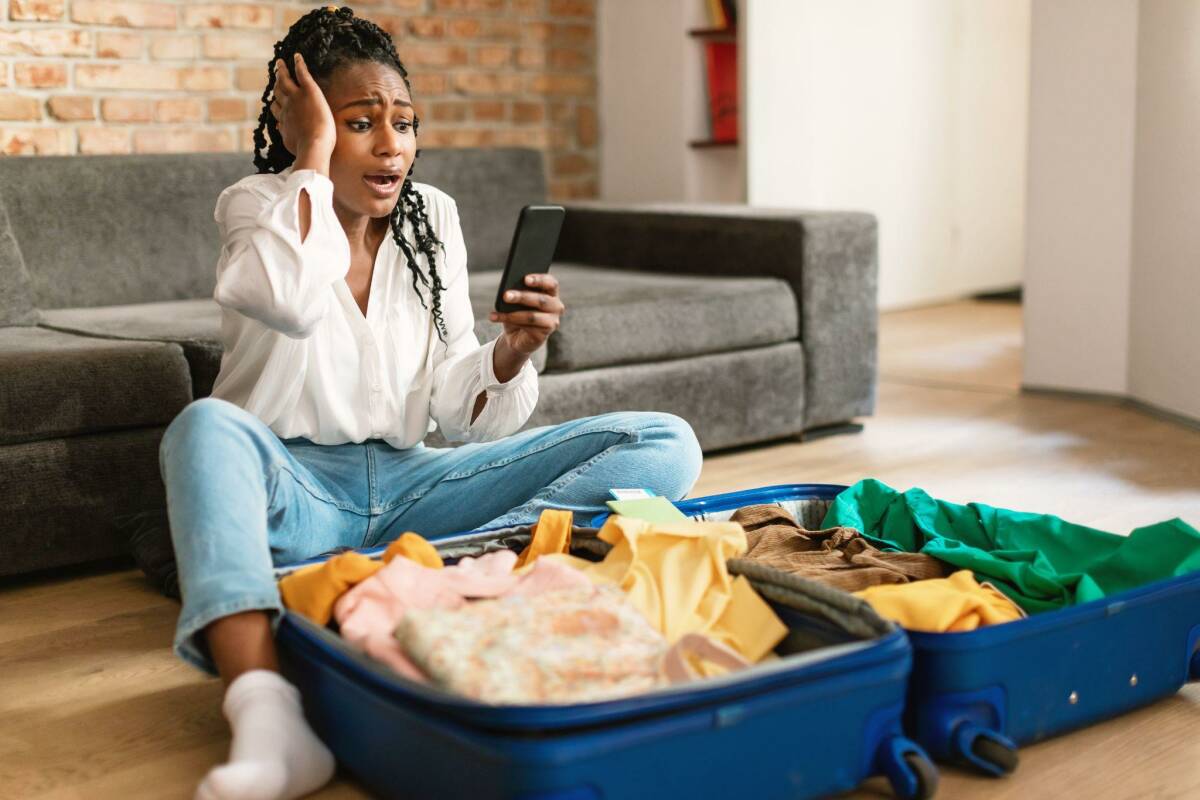 A woman sitting on the floor with an open luggage with no trip cancellation insurance.