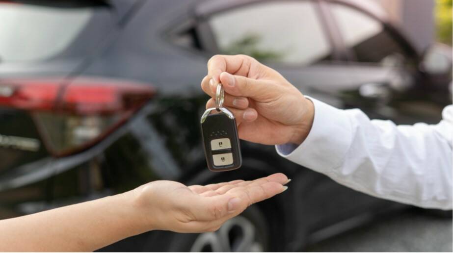  A hand passing over the keys to a rental car