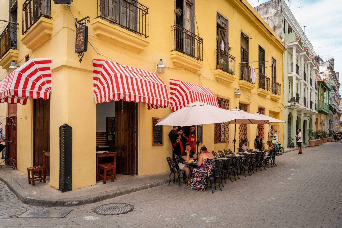 Patrons sit under red and white awnings at a cozy, family-owned paladar in Havana.