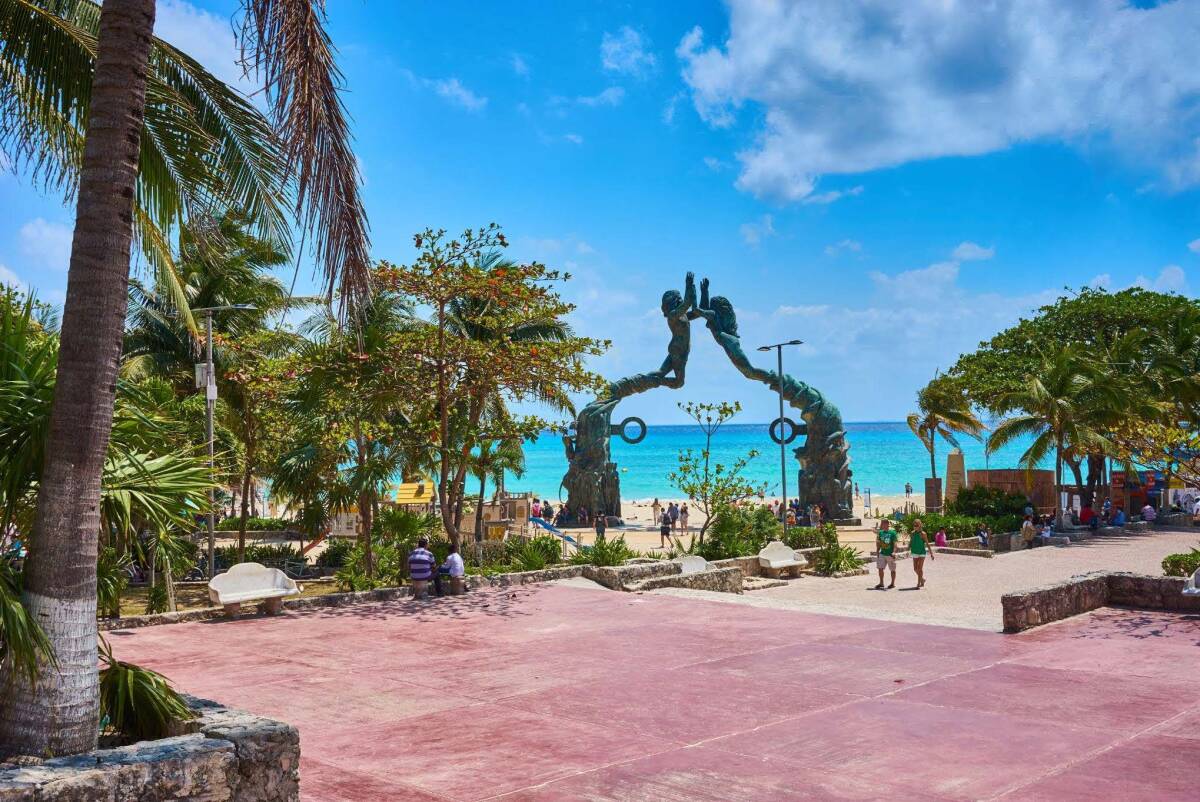 The vibrant beachfront at Playa del Carmen, with its iconic sculpture and palm trees, makes it a safe and picturesque destination in Mexico.