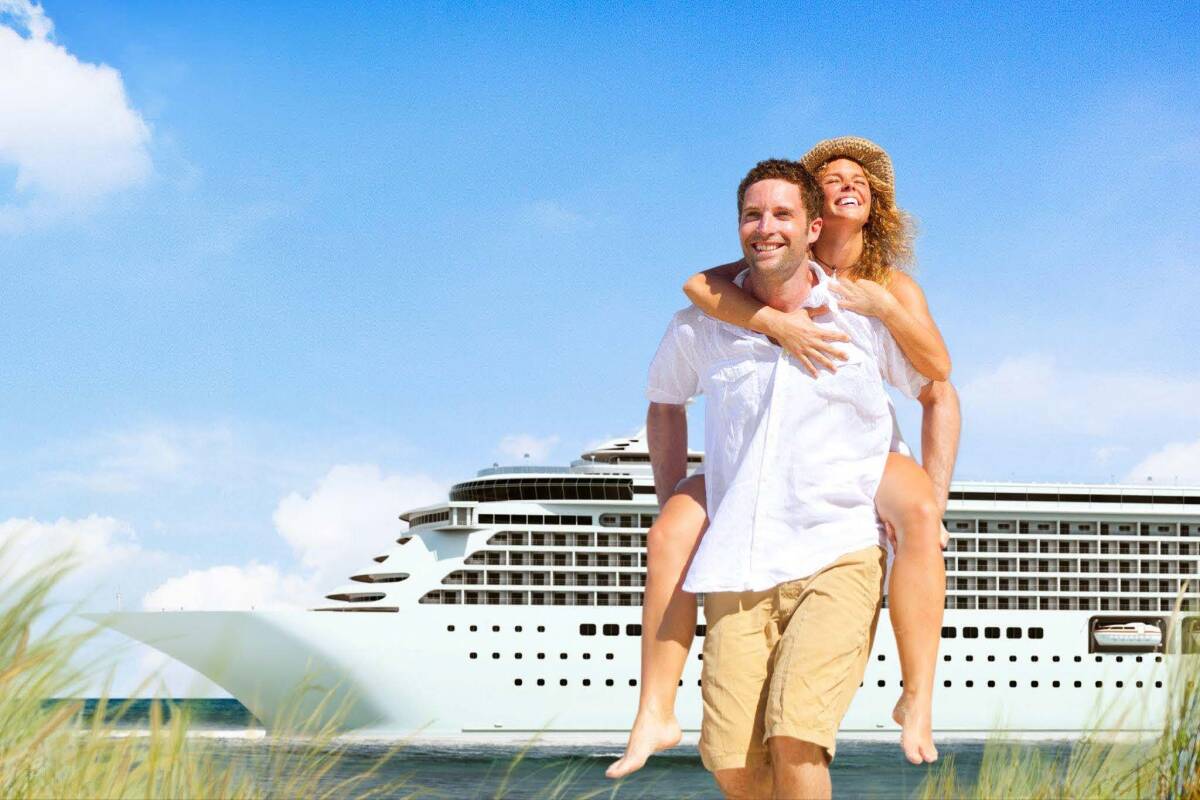 A couple enjoying a sunny day on the beach on their honeymoon with a large cruise ship in the background.