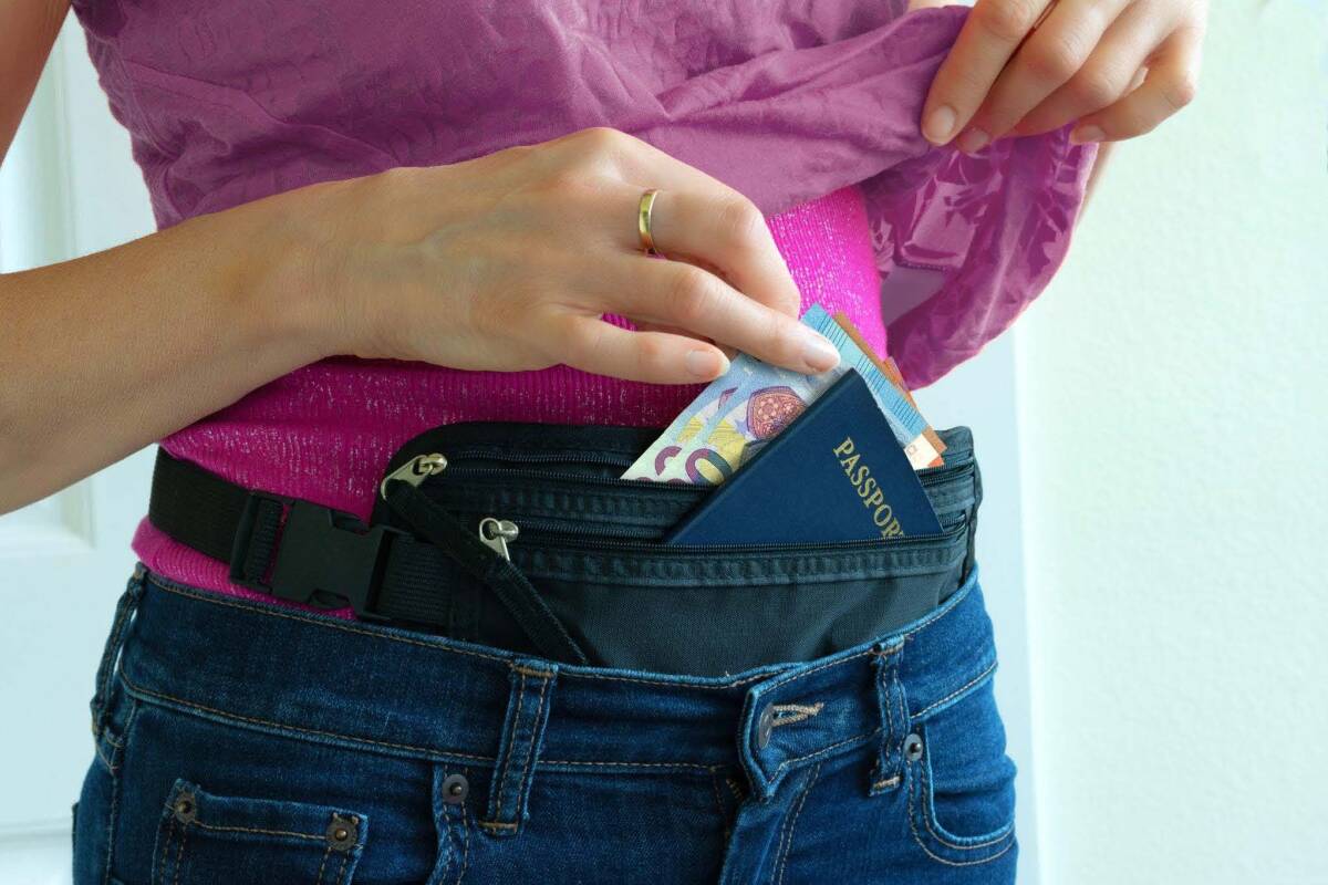 A traveler wearing a hidden RFID waist pouch with money and a passport.