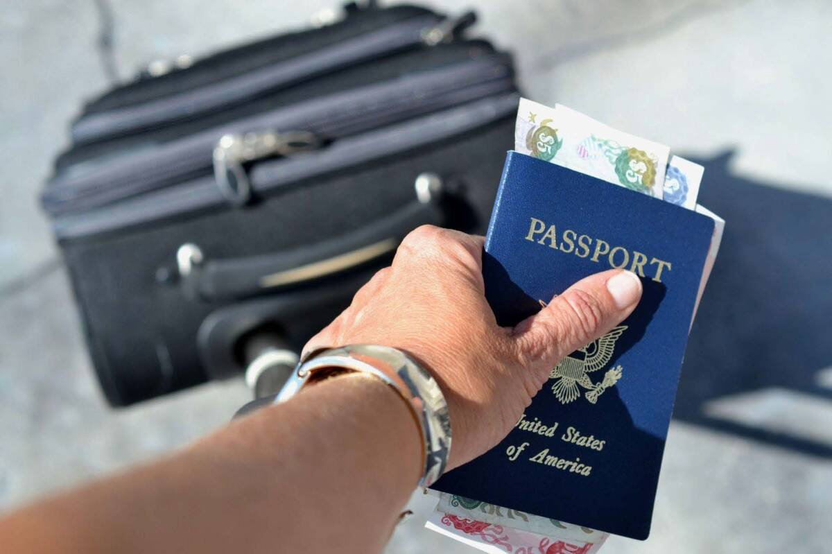 Close-up of a hand holding a passport and cash, highlighting the need for travel insurance for passport issues.