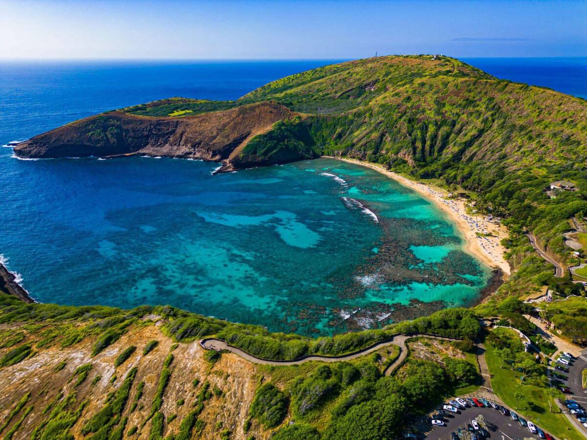 An aerial view of Hanauma Bay in Hawaii showcases its vibrant turquoise waters and lush green hills, a favorite warm place for winter travel.